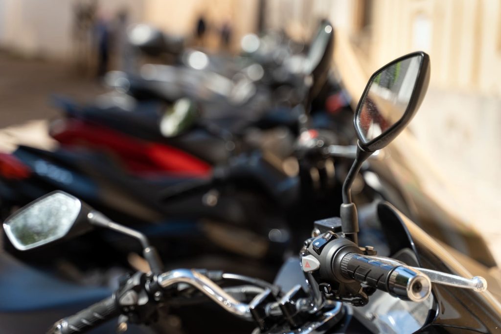 Espejos retrovisores y manillares de motocicletas aparcadas en hilera.